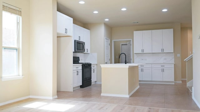 1024 Chad Loop, Round Rock, TX 78665 - kitchen featuring black range with electric stovetop, stainless steel microwave, a kitchen island with sink, tasteful backsplash, and healthy amount of natural light