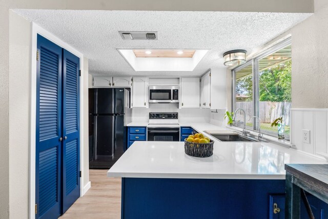 803 Lone Star Dr, Cedar Park, TX 78613 - kitchen with freestanding refrigerator, stainless steel microwave, range with electric stovetop, a textured ceiling, and a peninsula