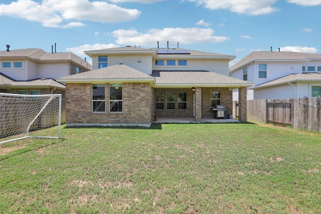 3200 Bravo Dr, Leander, TX 78641 - back of property featuring a fenced backyard, roof mounted solar panels, a patio area, brick siding, and roof with shingles