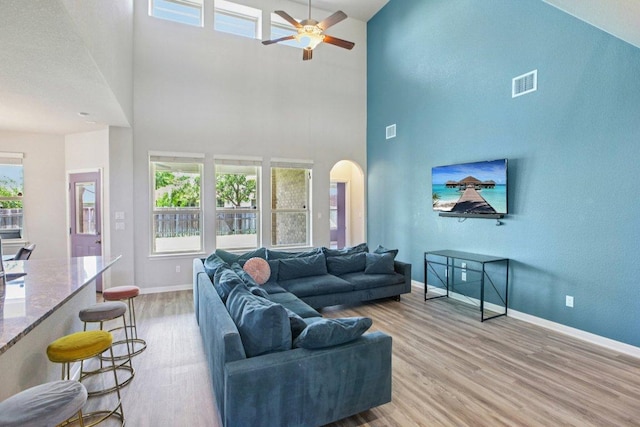 3200 Bravo Dr, Leander, TX 78641 - living room featuring light wood-style flooring, arched walkways, ceiling fan, and a towering ceiling
