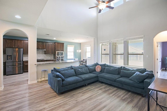 3200 Bravo Dr, Leander, TX 78641 - living area with arched walkways, light wood-style floors, ceiling fan, recessed lighting, and a high ceiling