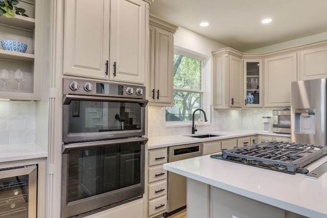 38 Cottondale Rd, The Hills, TX 78738 - kitchen featuring appliances with stainless steel finishes, beverage cooler, light countertops, tasteful backsplash, and glass insert cabinets