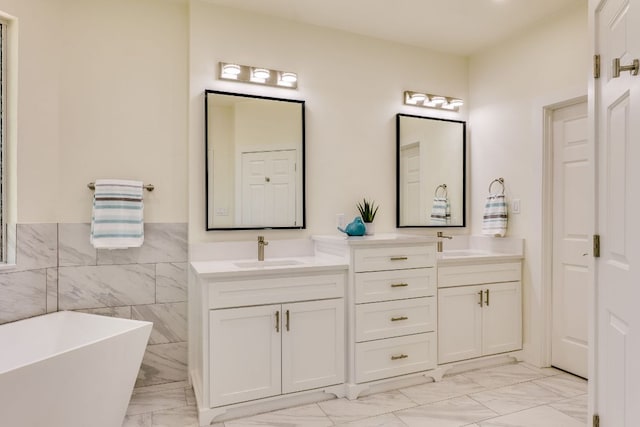 38 Cottondale Rd, The Hills, TX 78738 - full bath featuring marble look tiles, double vanity, a soaking tub, wainscoting, and tile walls