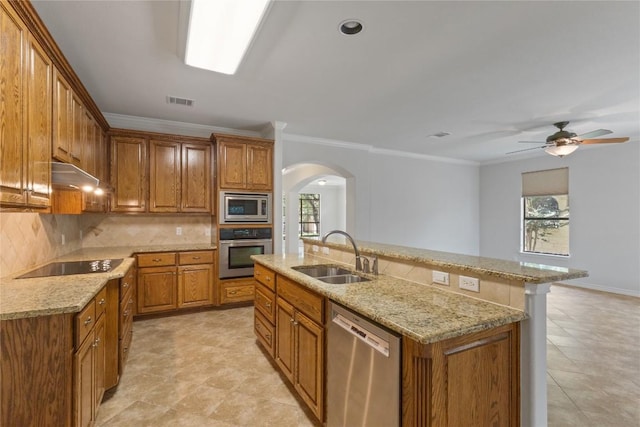 4921 Big Bend Trl, Georgetown, TX 78633 - kitchen featuring appliances with stainless steel finishes, arched walkways, brown cabinetry, tasteful backsplash, and crown molding