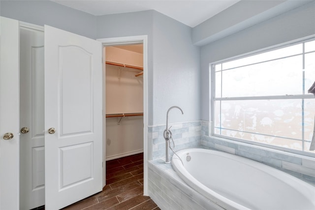 233 Thomas Dr, Martindale, TX 78655 - full bathroom featuring a bath, a spacious closet, and wood finished floors