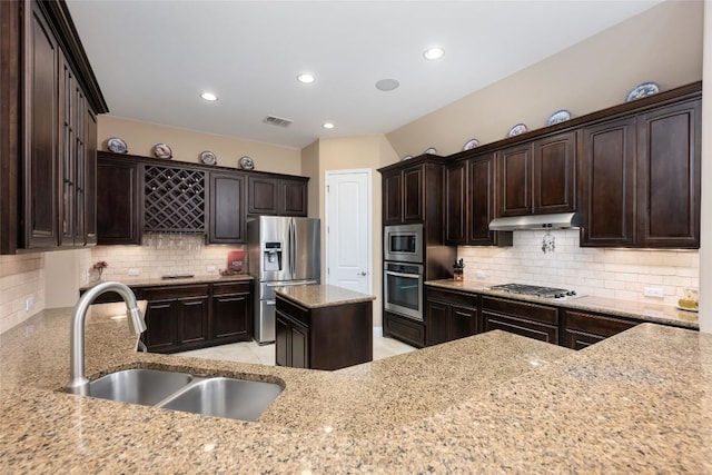 399 Whispering Wind Way, Austin, TX 78737 - kitchen with stainless steel appliances, under cabinet range hood, light stone counters, decorative backsplash, and recessed lighting