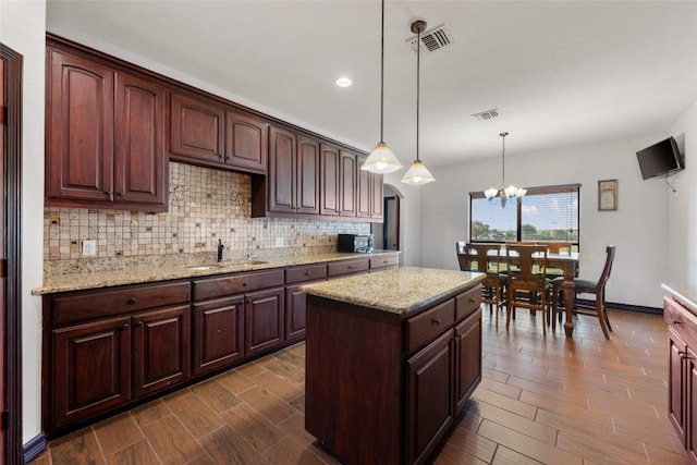 108 Whispering Pines Dr, Bastrop, TX 78602 - kitchen with dark wood finished floors, tasteful backsplash, a chandelier, hanging light fixtures, and light stone countertops