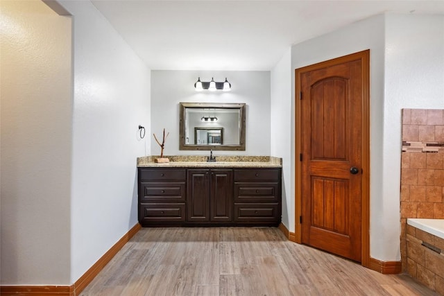 108 Whispering Pines Dr, Bastrop, TX 78602 - full bath featuring vanity, a relaxing tiled tub, and wood finished floors