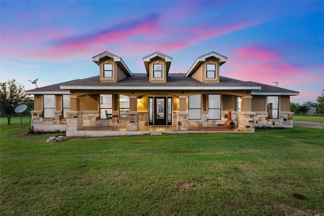 108 Whispering Pines Dr, Bastrop, TX 78602 - back of property at dusk featuring stone siding, covered porch, and a yard