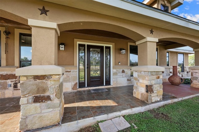 108 Whispering Pines Dr, Bastrop, TX 78602 - doorway to property with covered porch, stucco siding, and stone siding
