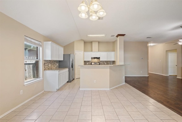 1008 NE Chippewa St, Round Rock, TX 78665 - kitchen with open floor plan, decorative backsplash, stainless steel fridge, white cabinetry, and lofted ceiling