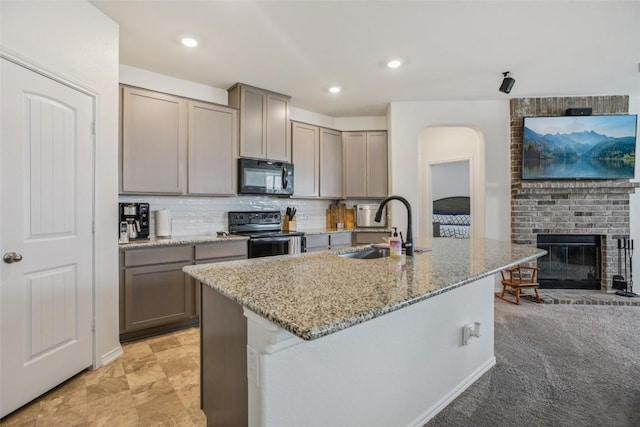 657 Bailey Park Dr, Jarrell, TX 76537 - kitchen featuring black appliances, light stone counters, gray cabinetry, tasteful backsplash, and a kitchen island with sink