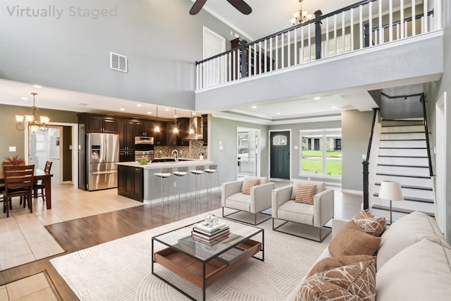 11611 Quarter Horse Trl, Austin, TX 78750 - living room featuring a chandelier, stairs, light wood-style flooring, ceiling fan, and ornamental molding