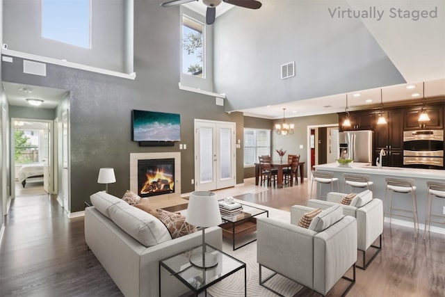 11611 Quarter Horse Trl, Austin, TX 78750 - living area featuring a towering ceiling, wood finished floors, healthy amount of natural light, a ceiling fan, and a glass covered fireplace