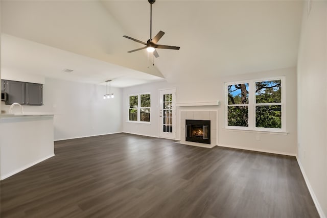 6900 Tesoro Trl, Austin, TX 78729 - unfurnished living room with dark wood-style floors, a tiled fireplace, ceiling fan, and high vaulted ceiling