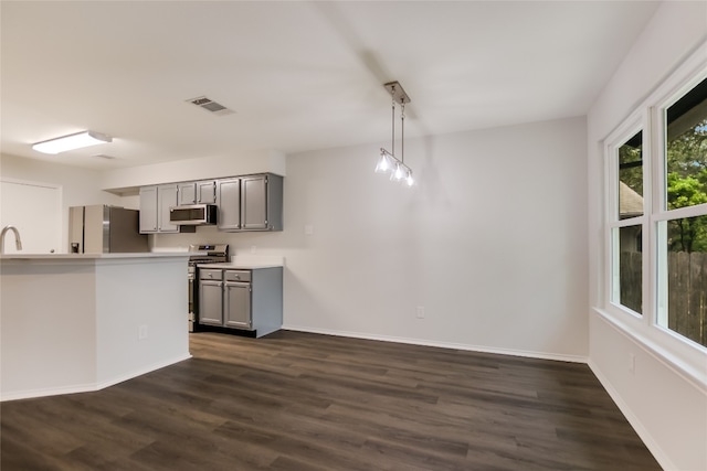 6900 Tesoro Trl, Austin, TX 78729 - kitchen with stainless steel appliances, gray cabinetry, dark wood-style floors, light countertops, and hanging light fixtures