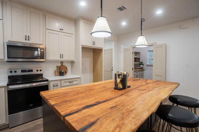 118 Kipapa Ct, Bastrop, TX 78602 - kitchen featuring appliances with stainless steel finishes, wooden counters, hanging light fixtures, a center island, and a breakfast bar area