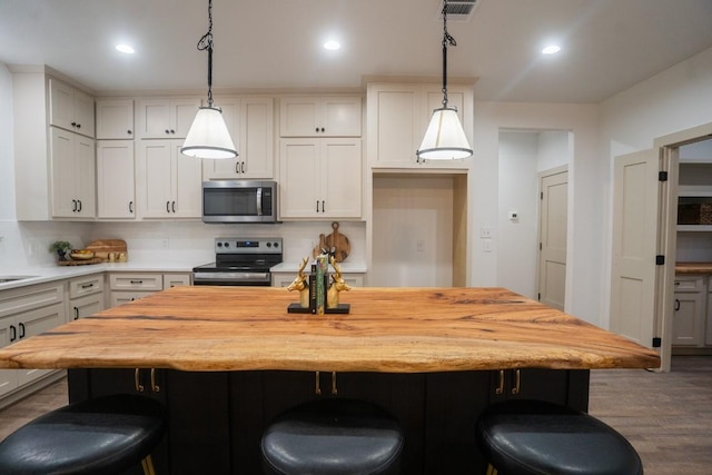 118 Kipapa Ct, Bastrop, TX 78602 - kitchen featuring appliances with stainless steel finishes, butcher block countertops, a kitchen bar, dark wood-type flooring, and recessed lighting