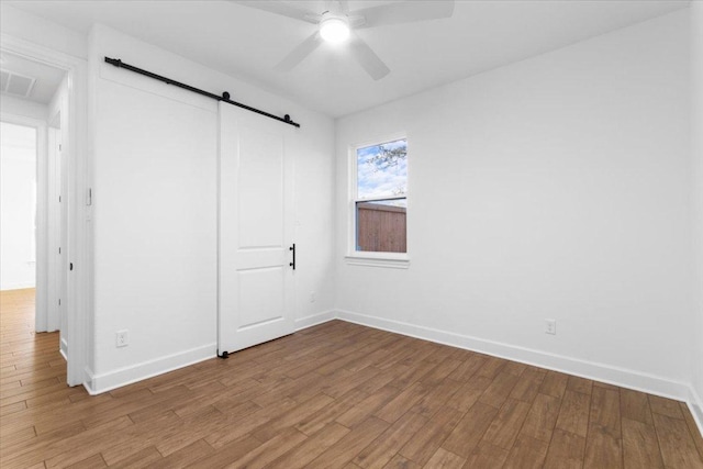 4121 Turning Leaf Dr, Nolanville, TX 76559 - unfurnished bedroom with a barn door, light wood-type flooring, and a ceiling fan