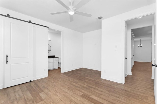 4113 Turning Leaf Dr, Nolanville, TX 76559 - unfurnished bedroom with a barn door, light wood-type flooring, and a chandelier
