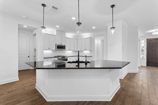4113 Turning Leaf Dr, Nolanville, TX 76559 - kitchen with appliances with stainless steel finishes, ornamental molding, dark countertops, dark wood-type flooring, and white cabinetry