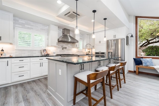 4604 Fawnwood Cv, Austin, TX 78735 - kitchen with wall chimney exhaust hood, stainless steel appliances, light wood-type flooring, plenty of natural light, and recessed lighting