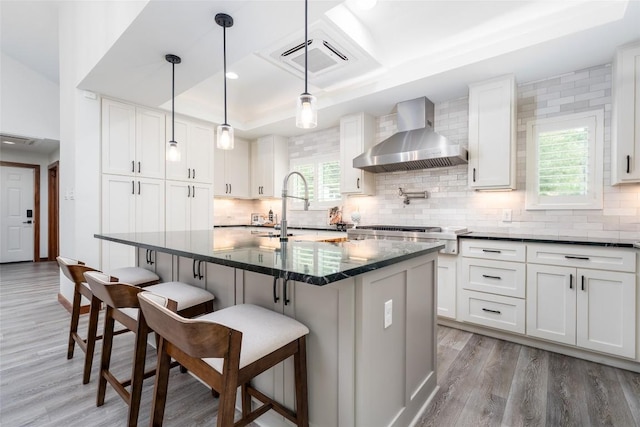 4604 Fawnwood Cv, Austin, TX 78735 - kitchen featuring wall chimney exhaust hood, stainless steel gas stovetop, light wood-style floors, healthy amount of natural light, and recessed lighting