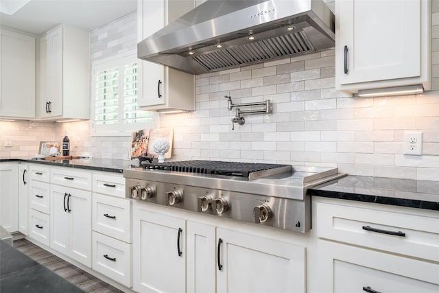 4604 Fawnwood Cv, Austin, TX 78735 - kitchen with wall chimney range hood, stainless steel gas cooktop, white cabinets, decorative backsplash, and dark stone countertops