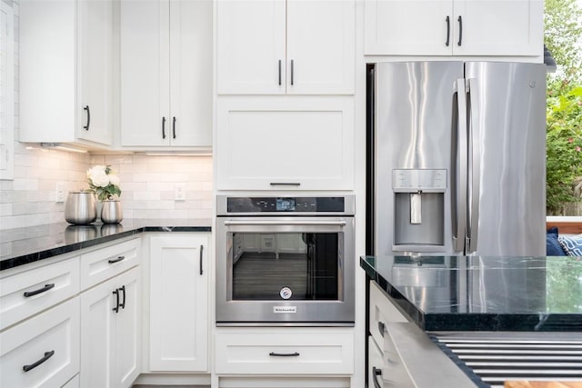4604 Fawnwood Cv, Austin, TX 78735 - kitchen featuring stainless steel appliances, decorative backsplash, dark stone countertops, and white cabinets