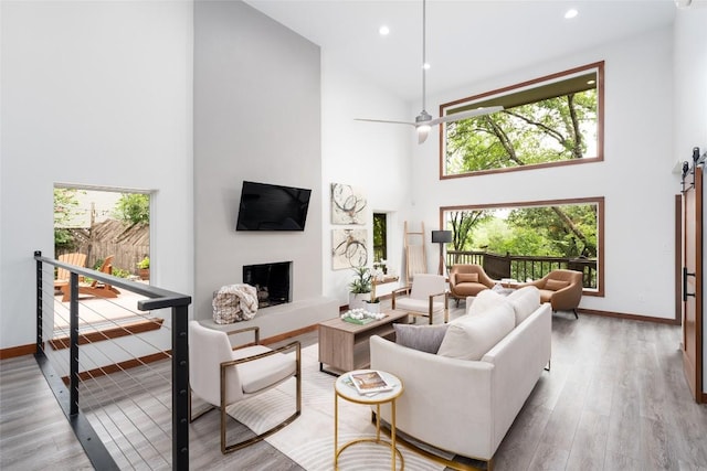 4604 Fawnwood Cv, Austin, TX 78735 - living room featuring high vaulted ceiling, a fireplace with raised hearth, plenty of natural light, wood finished floors, and recessed lighting