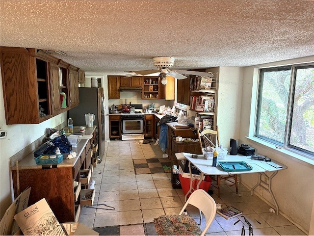 8306 Hanbridge Ln, Austin, TX 78736 - kitchen with open shelves, freestanding refrigerator, light countertops, a ceiling fan, and brown cabinetry
