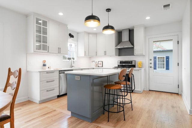 502 E 46th St, Austin, TX 78751 - kitchen with wall chimney range hood, appliances with stainless steel finishes, a kitchen island, healthy amount of natural light, and recessed lighting