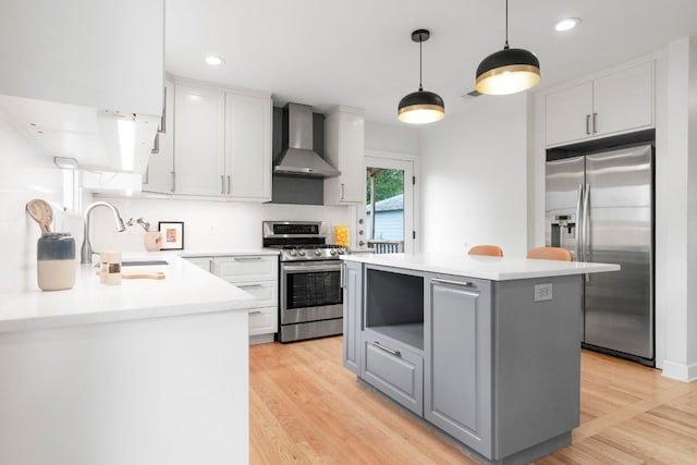 502 E 46th St, Austin, TX 78751 - kitchen featuring appliances with stainless steel finishes, wall chimney exhaust hood, a kitchen island, gray cabinetry, and light countertops