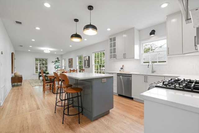 502 E 46th St, Austin, TX 78751 - kitchen with stainless steel dishwasher, light countertops, a breakfast bar, a kitchen island, and light wood-style flooring