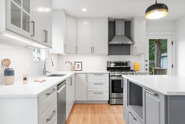 502 E 46th St, Austin, TX 78751 - kitchen with wall chimney range hood, stainless steel appliances, light wood-style floors, white cabinetry, and recessed lighting