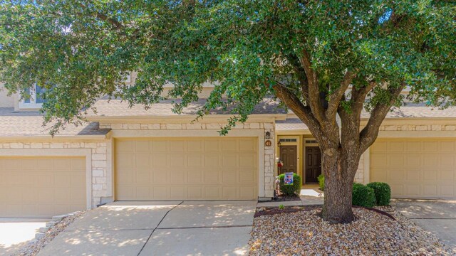 3300 Forest Creek Dr Unit 45, Round Rock, TX 78664 - view of front of property with a shingled roof, concrete driveway, an attached garage, and stone siding