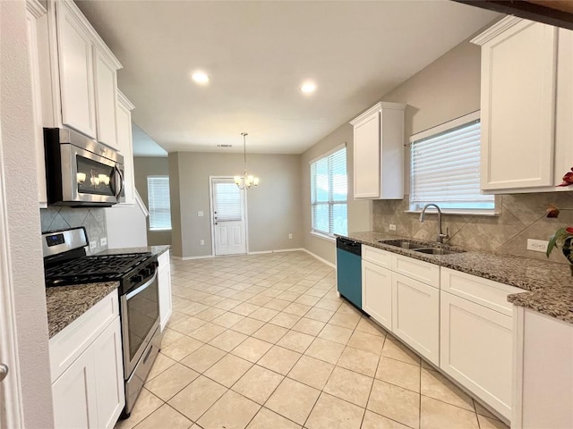 139 Diamondback Cv, Buda, TX 78610 - kitchen with stainless steel appliances, a chandelier, tasteful backsplash, white cabinets, and light tile patterned floors