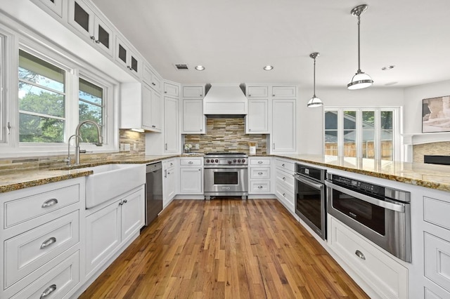 2507 Hartford Rd, Austin, TX 78703 - kitchen featuring stainless steel appliances, premium range hood, white cabinetry, light stone counters, and recessed lighting