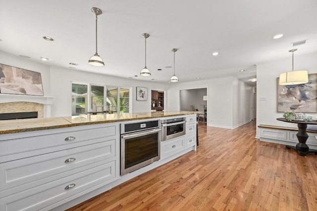 2507 Hartford Rd, Austin, TX 78703 - kitchen with oven, recessed lighting, light wood-type flooring, hanging light fixtures, and white cabinetry