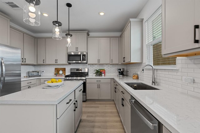 13506 Grand Central Dr, Pflugerville, TX 78660 - kitchen with stainless steel appliances, gray cabinetry, backsplash, light stone counters, and recessed lighting