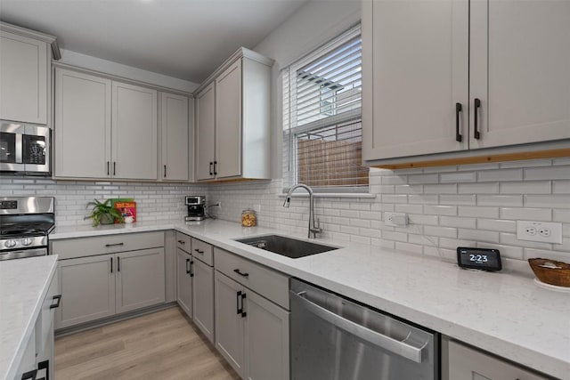 13506 Grand Central Dr, Pflugerville, TX 78660 - kitchen with appliances with stainless steel finishes, gray cabinets, light wood finished floors, and backsplash