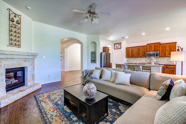 5521 Texas Bluebell Dr, Spicewood, TX 78669 - living area featuring arched walkways, a ceiling fan, wood finished floors, a stone fireplace, and recessed lighting