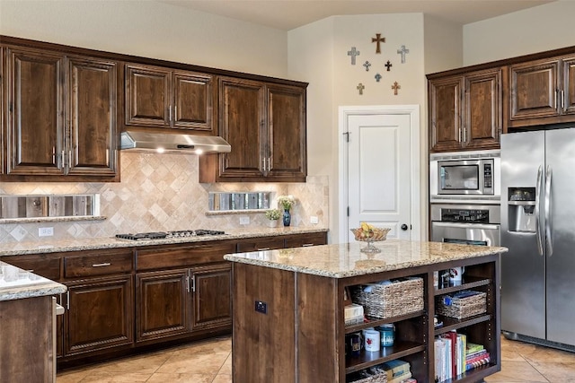 8709 Fescue Ln, Austin, TX 78738 - kitchen featuring appliances with stainless steel finishes, light stone counters, under cabinet range hood, light tile patterned floors, and backsplash