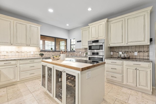 13100 N Ridge Cir, Leander, TX 78641 - kitchen with cream cabinets, black electric stovetop, stainless steel double oven, wood counters, and decorative backsplash