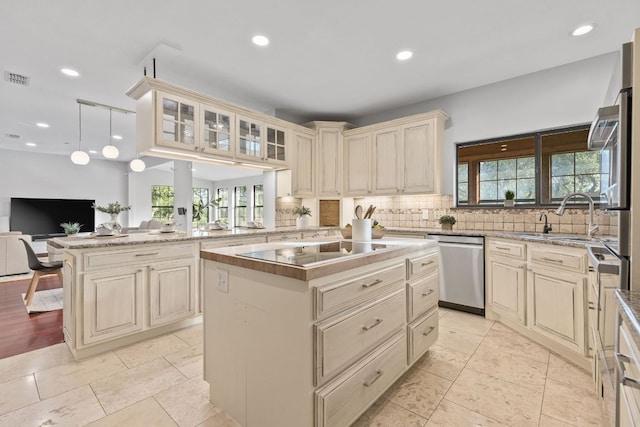 13100 N Ridge Cir, Leander, TX 78641 - kitchen with cream cabinets, stainless steel dishwasher, black electric stovetop, healthy amount of natural light, and recessed lighting