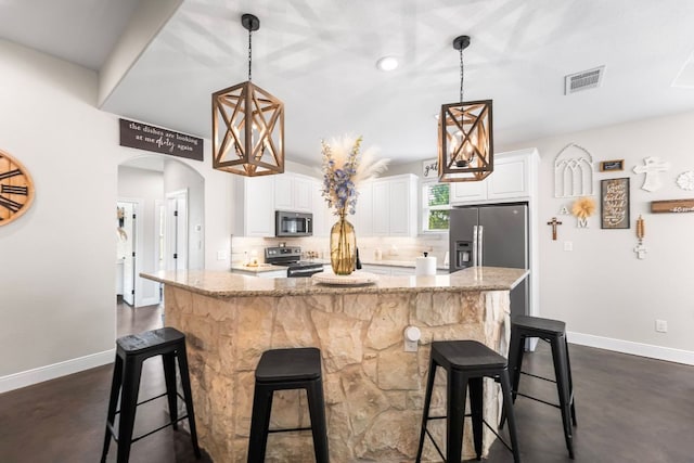 102 Moku Ct, Bastrop, TX 78602 - kitchen featuring stainless steel appliances, a center island, arched walkways, white cabinetry, and light stone counters