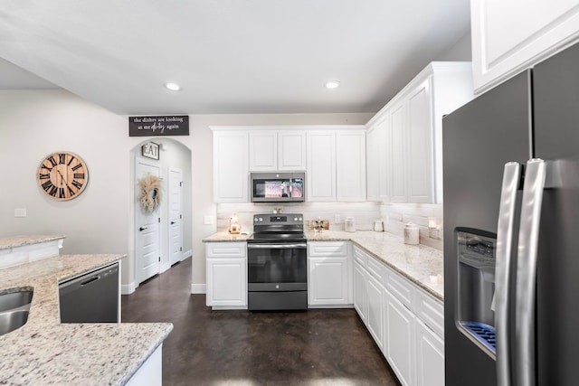 102 Moku Ct, Bastrop, TX 78602 - kitchen with appliances with stainless steel finishes, finished concrete flooring, backsplash, white cabinetry, and arched walkways