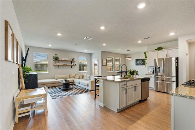 200 Mais Dr, Georgetown, TX 78626 - kitchen featuring stainless steel appliances, open floor plan, light wood-type flooring, light stone countertops, and recessed lighting
