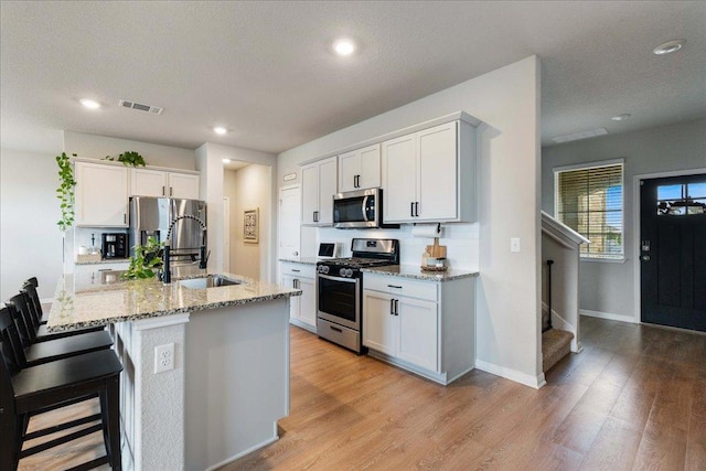 200 Mais Dr, Georgetown, TX 78626 - kitchen featuring appliances with stainless steel finishes, light stone countertops, light wood-style floors, white cabinetry, and recessed lighting