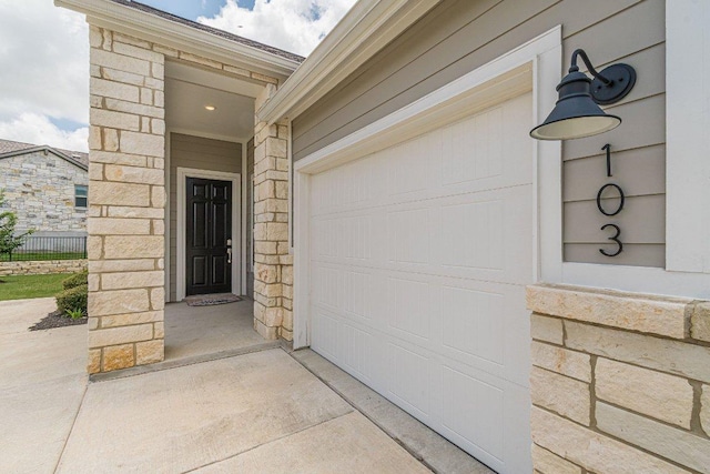 116 Mulligan Dr Unit 103, San Marcos, TX 78666 - property entrance with driveway, stone siding, and a garage
